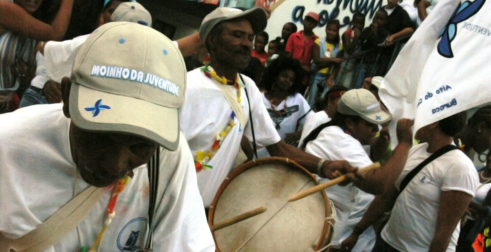 Percussionistas do Moinho da Juventude em desfile na Cova da Moura, com tambores e a bandeira da associação